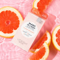 Vitamin Recharge Mani in a Box on pink background with grapefruit slices