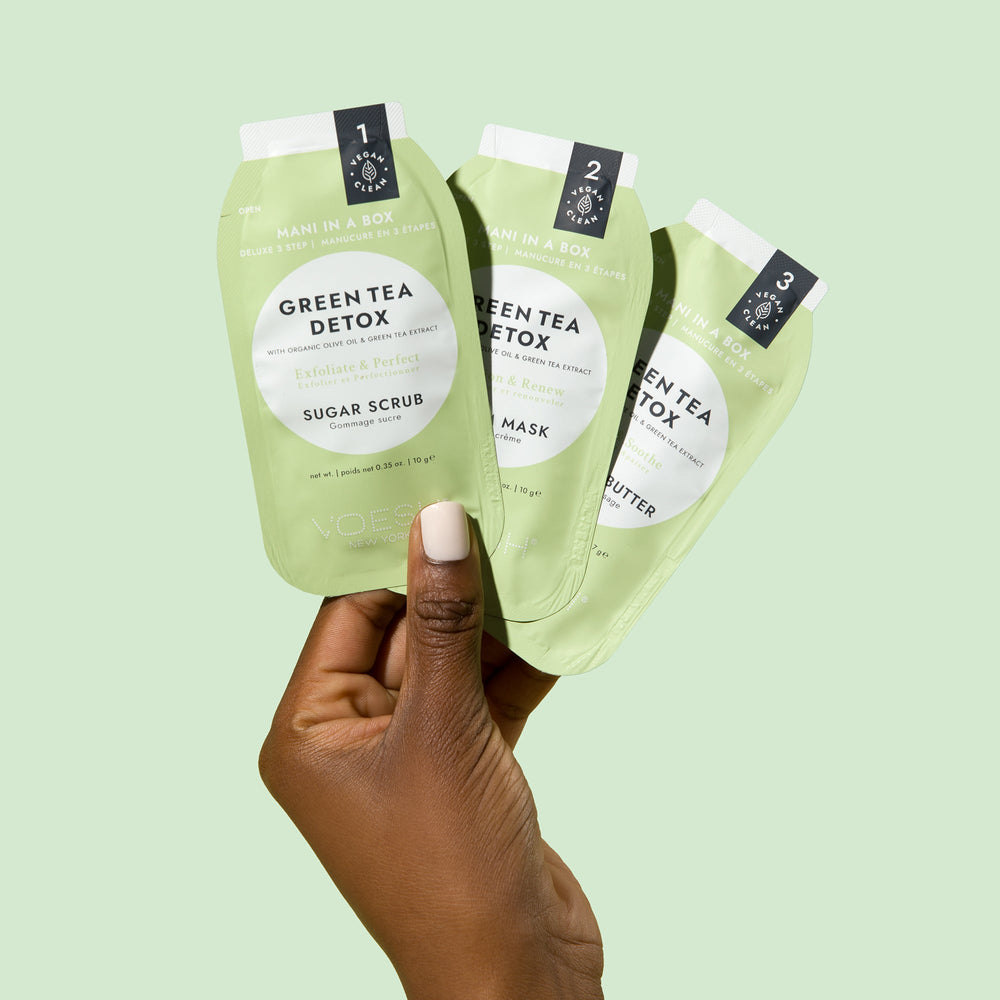Woman holding satchet of Green Tea Detox Mani in a Box on green background