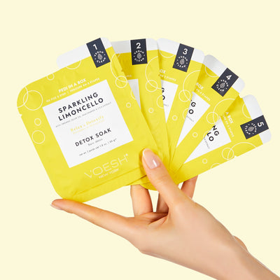 Hand holding all 5 steps of the O2 Fizz Pedi in a Box