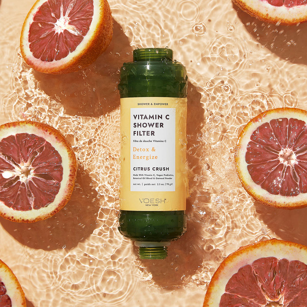 Vitamin C Shower Filter Citrus Crush next to orange slices on an orange water background.