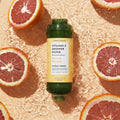 Vitamin C Shower Filter Citrus Crush next to orange slices on an orange water background.