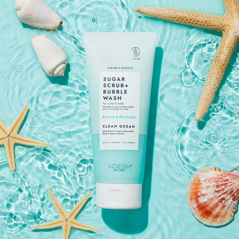 Sugar Scrub + Bubble Wash Clean Ocean next to starfish and seashells on a blue water background.