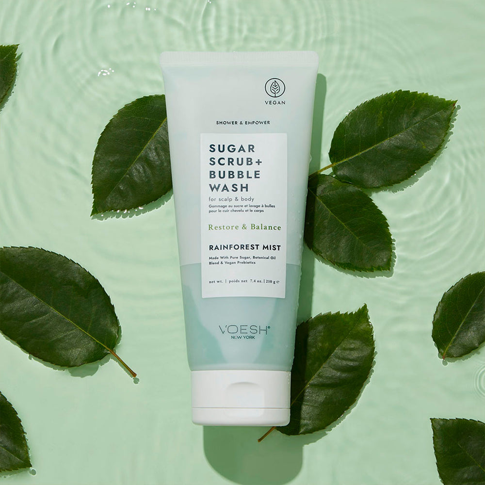 Sugar Scrub + Bubble Wash Rainforest Mist next to green leaves on a green water background.