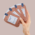Woman's hand holding chocolate love 4 step packets on light brown background