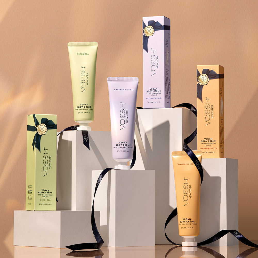 VOESH’s Tangerine Glow, Lavender Land, and Green Tea Vegan Body Crèmes, displayed on white boxes, in front of a brown background.
