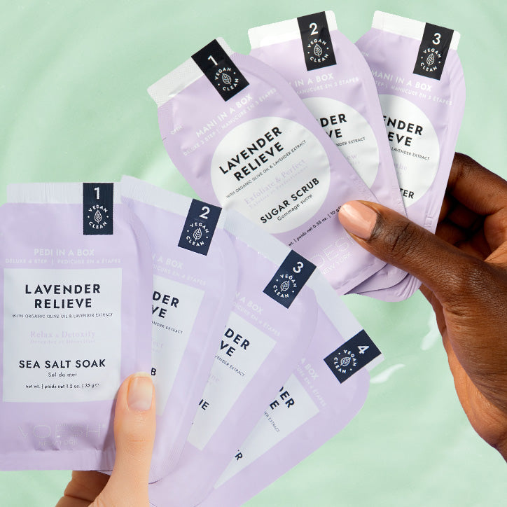 Two hands holding lavender relieve mani and pedi kits