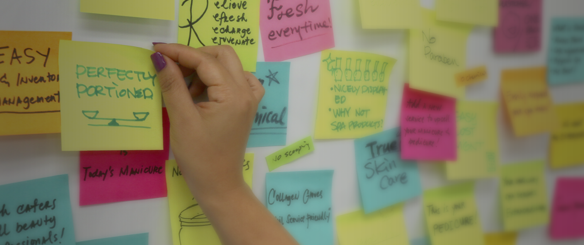 Women sticking post-its on a board with company ideas for our Story