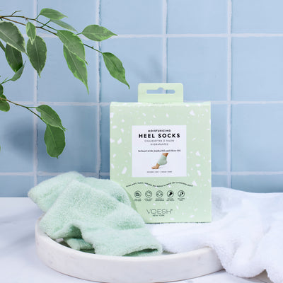 Moisturizing Heel Socks with white towel and leaves in a blue tiled background