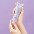 Female hands holding VOESH’s Lavender Land Vegan Body Crème, in front of a purple background, for healthy, hydrated skin.