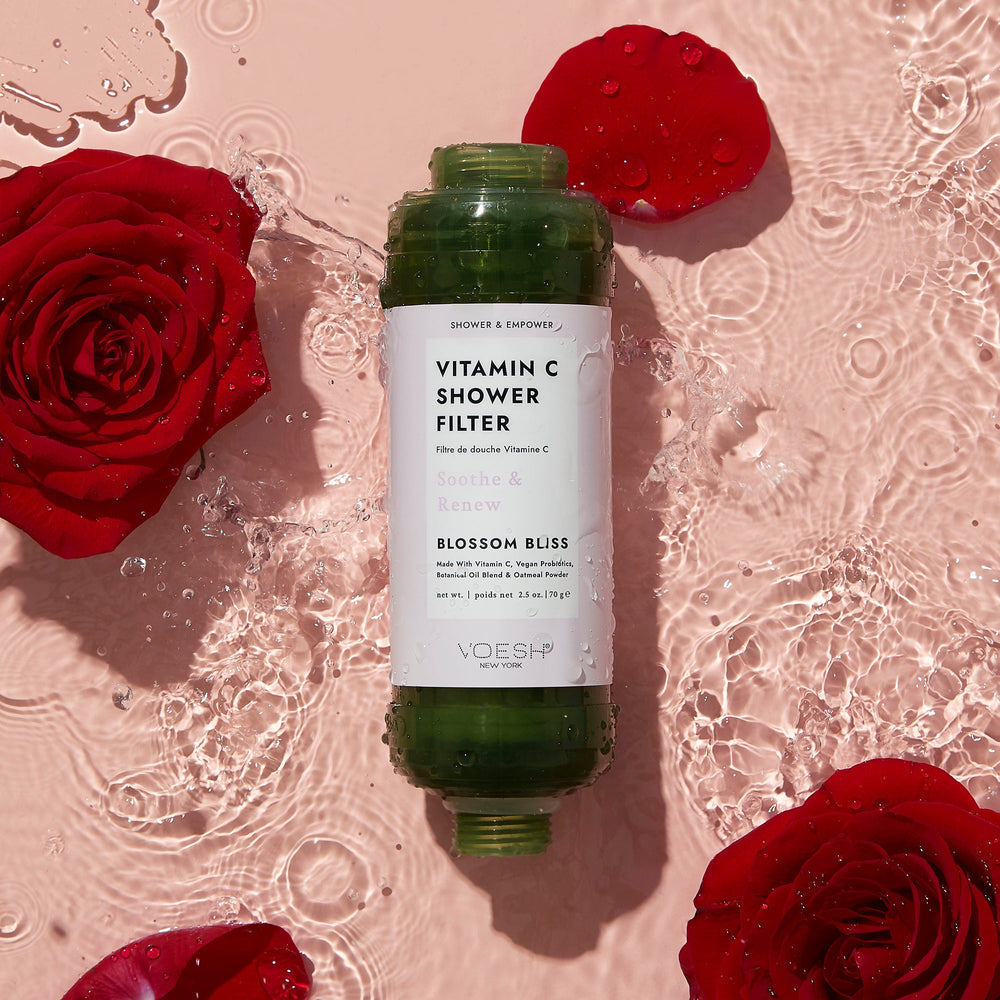 Blossom Bliss Vitamin C Shower Filter in water with rose flowers surrounding it on a pink background
