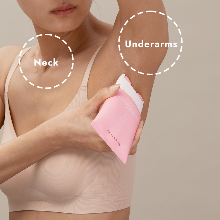 Woman in her bra and underwear using Smooth’d Body Refining Roller Crème on her underarm area, pictured on a tan background.